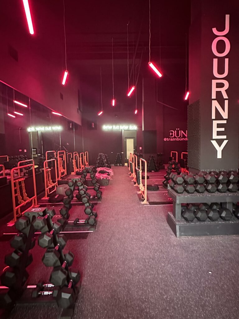 Modern gym interior with red lighting and dumbbells.