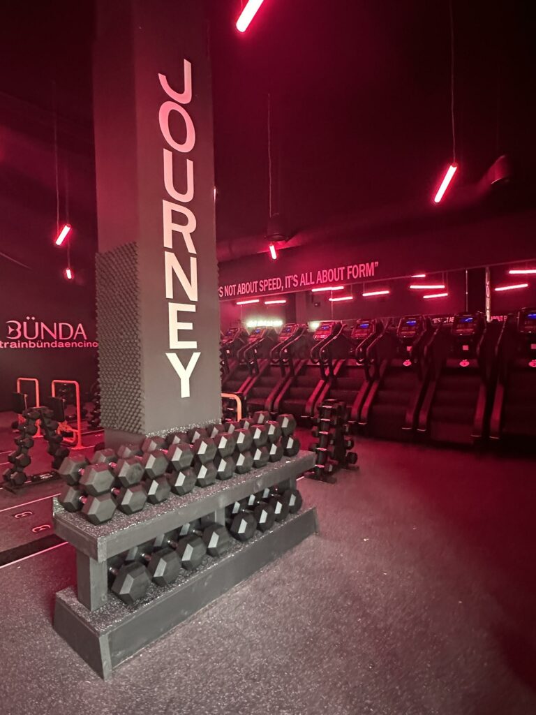 Modern gym interior with weights and red neon lights.