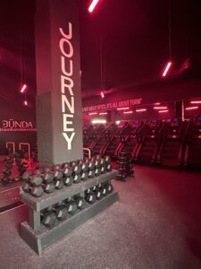 Modern gym interior with red lighting and dumbbell racks.