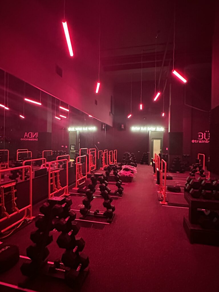 Modern gym interior with red neon lights and equipment.