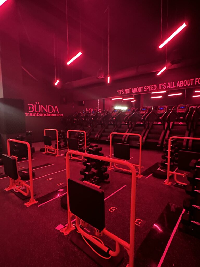 Red-lit gym interior with treadmills and exercise equipment.
