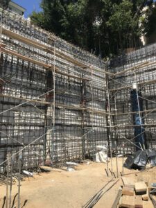 Multi-level construction scaffolding with rebar and trees.