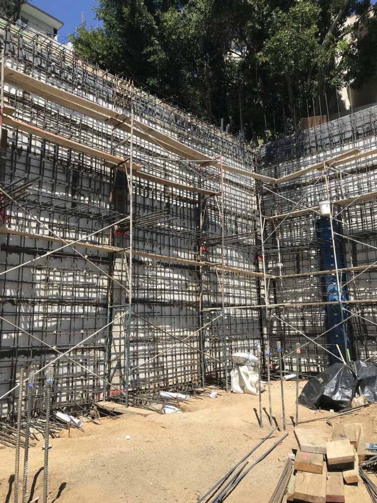 Multi-level construction scaffolding with rebar and trees.