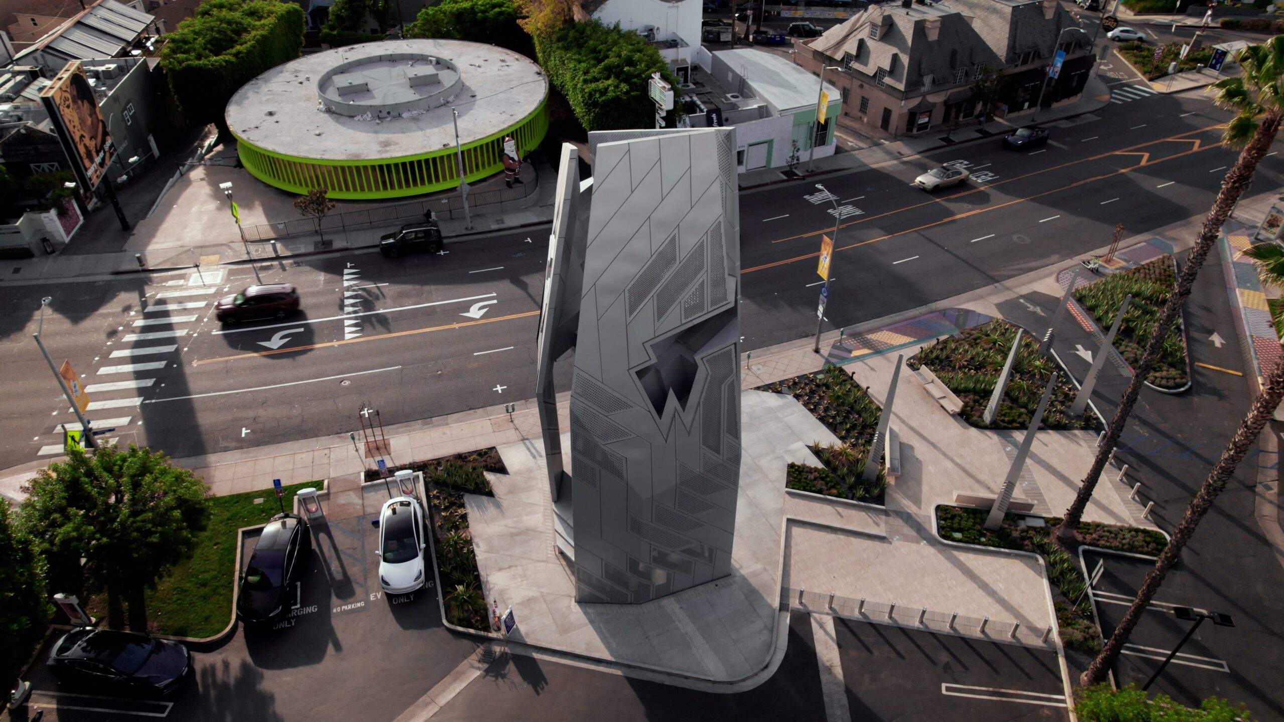 Aerial view of urban street intersection with unique building.
