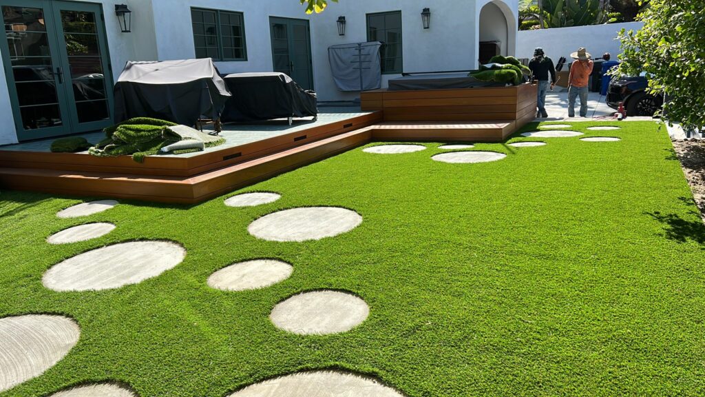Backyard with synthetic grass and round stepping stones.