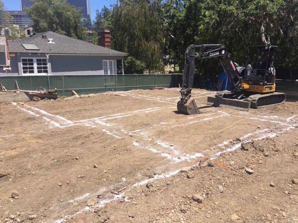 Construction site with excavator and marked ground.