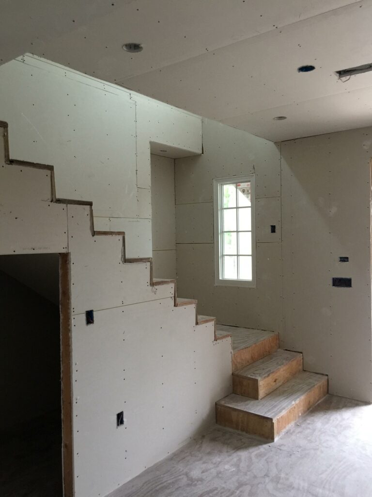 Interior construction, drywall installation, unfinished staircase.