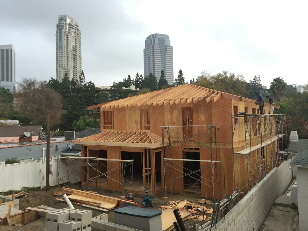Construction of house with workers and urban backdrop.