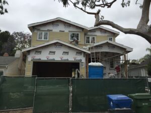 Workers installing siding on residential home under construction.