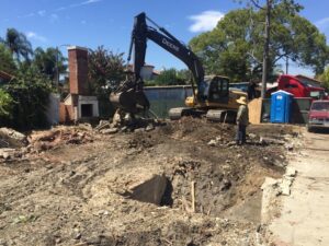 Excavator and worker at a demolition site.