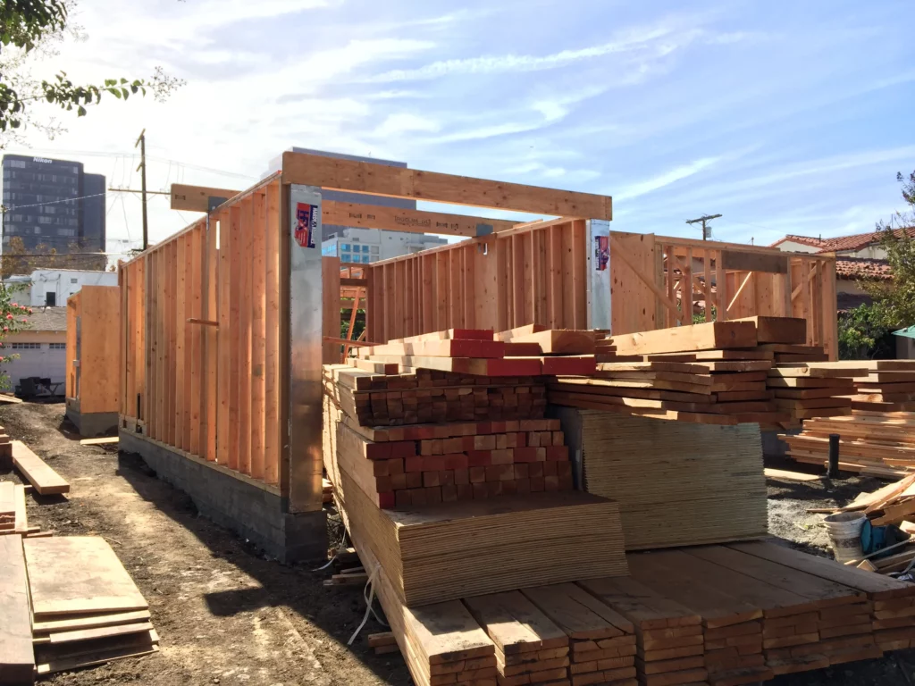 Wood-framed building construction site with lumber stacks.