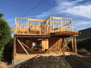 Wooden house frame construction site under blue sky.