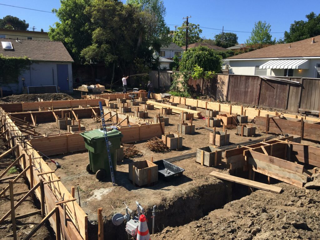 Residential construction site with wooden framing and trenches.