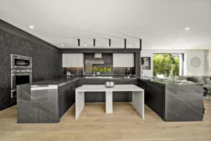 Modern kitchen interior with black countertops and wooden floor.