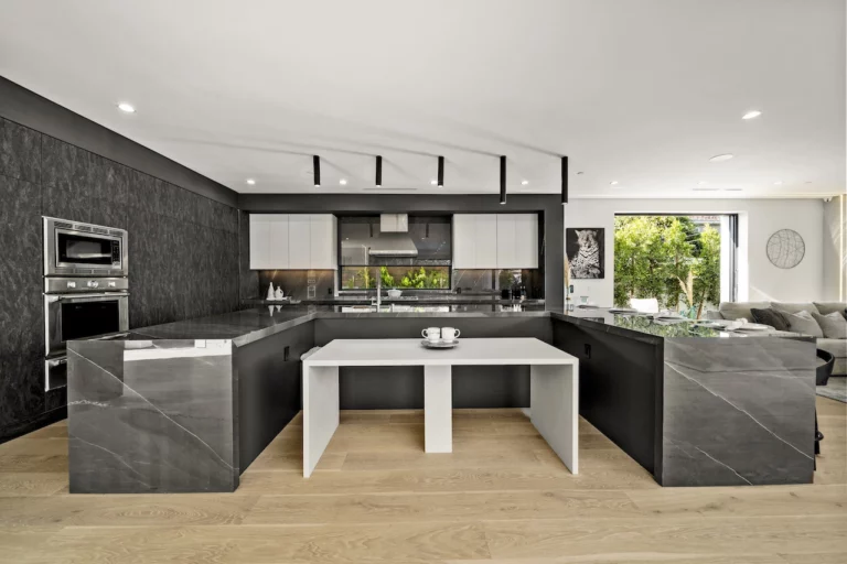Modern kitchen interior with black countertops and wooden floor.