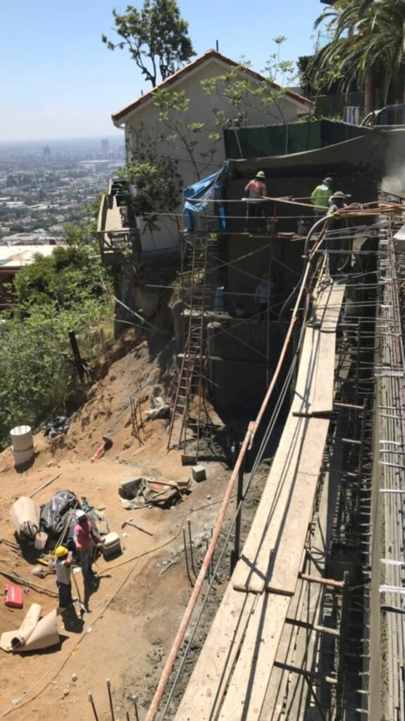 Workers on scaffolding at hillside construction site.