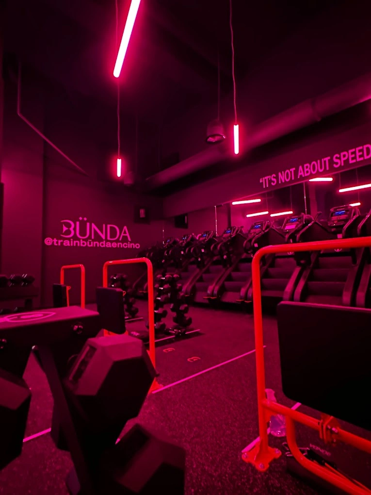 Red-lit gym with treadmills and weights.