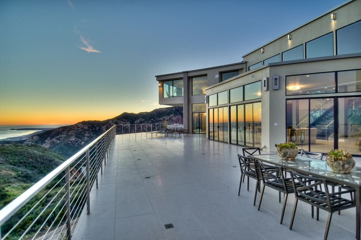 Modern house patio with ocean view at sunset.