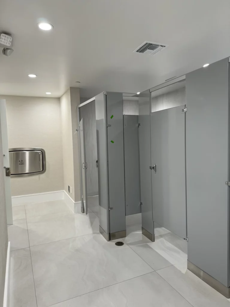 Modern restroom interior with stall doors and tiled floor.