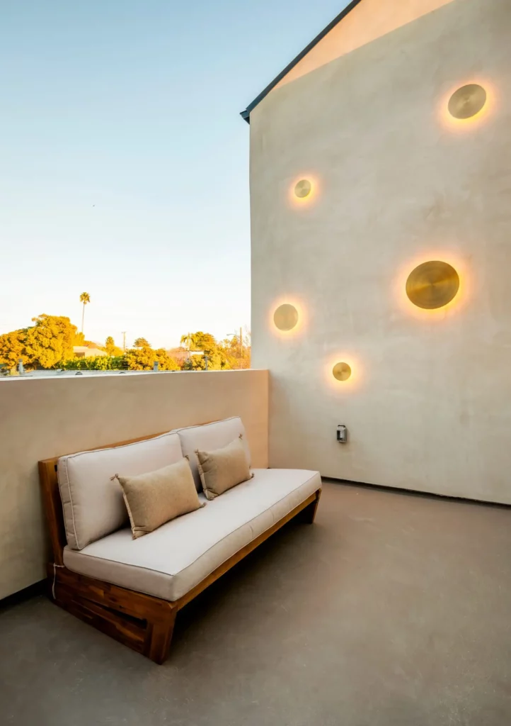 Modern outdoor sofa on concrete balcony with wall lights