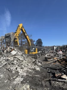 Yellow excavator clearing debris at disaster site