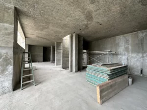 Unfinished concrete building interior with columns and materials