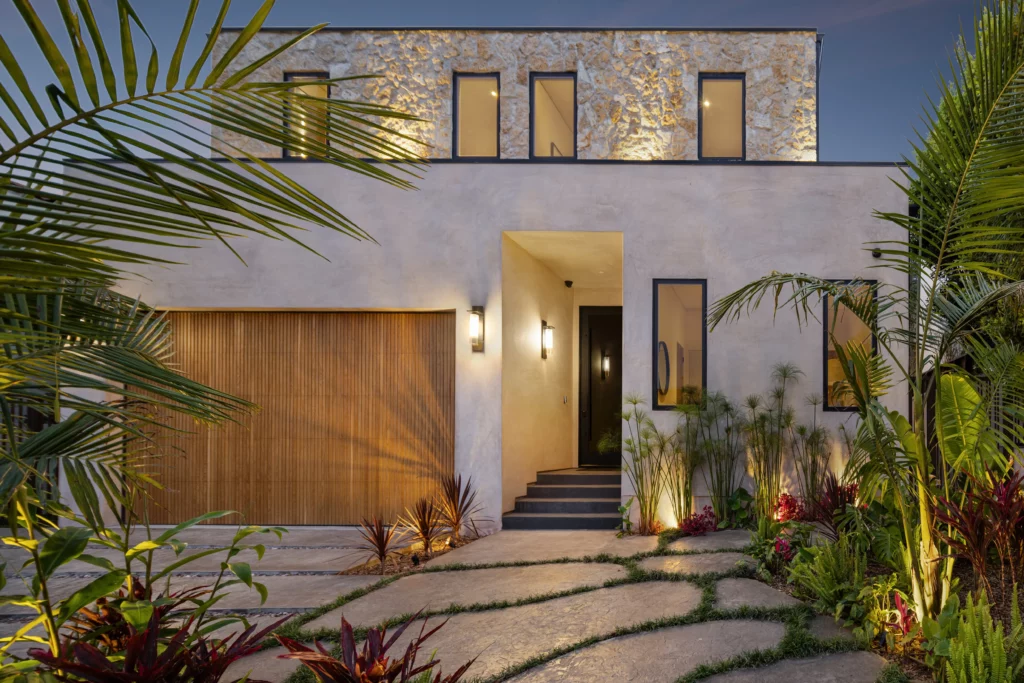 Modern luxury home exterior at dusk with tropical plants