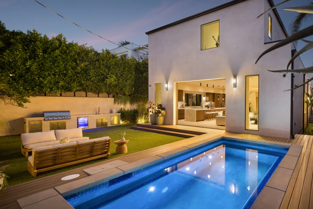 Luxurious backyard with pool and outdoor kitchen at dusk