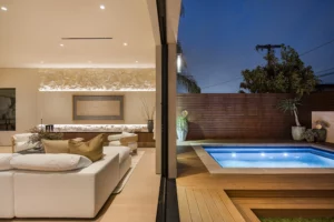 Luxurious modern living room next to outdoor pool at night